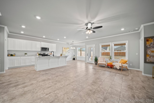 kitchen with ornamental molding, an island with sink, white cabinets, ceiling fan, and light tile floors