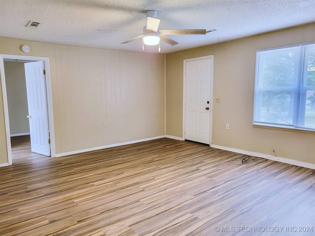 unfurnished room featuring ceiling fan, light wood-type flooring, and a textured ceiling