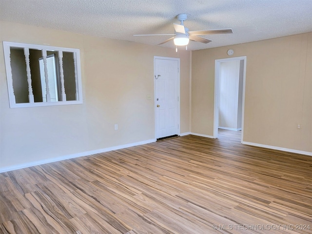 empty room featuring light wood-type flooring, a textured ceiling, and ceiling fan