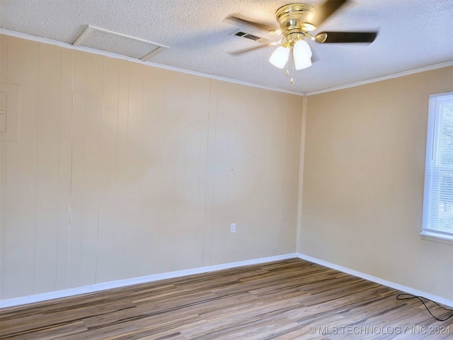 empty room with a textured ceiling, ceiling fan, wood-type flooring, and ornamental molding