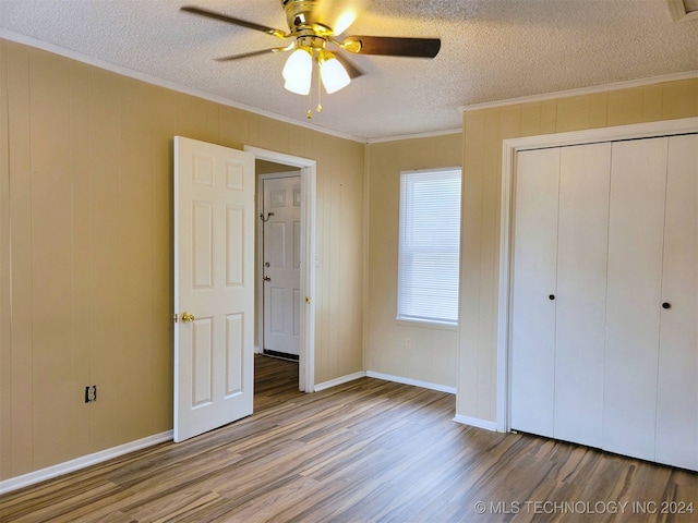 unfurnished bedroom featuring ceiling fan, ornamental molding, a textured ceiling, a closet, and hardwood / wood-style flooring