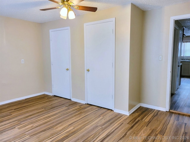 unfurnished bedroom featuring hardwood / wood-style flooring, ceiling fan, sink, and a textured ceiling