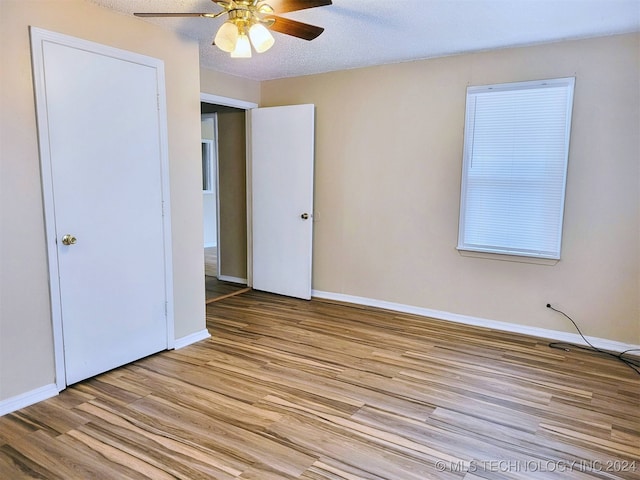 unfurnished bedroom with a closet, a textured ceiling, light hardwood / wood-style floors, and ceiling fan