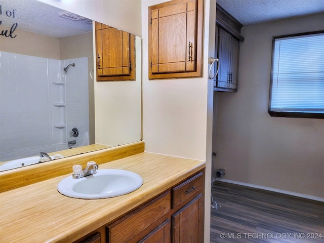 bathroom featuring vanity, wood-type flooring, a textured ceiling, and bathtub / shower combination