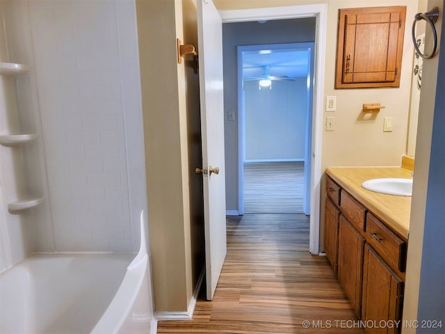 bathroom with washtub / shower combination, hardwood / wood-style floors, vanity, and ceiling fan