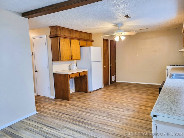 kitchen with a textured ceiling, ceiling fan, light hardwood / wood-style flooring, beamed ceiling, and white fridge