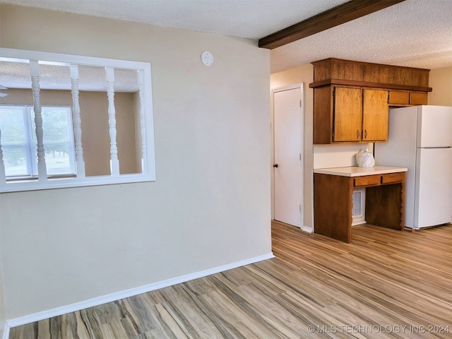 kitchen with a textured ceiling, light hardwood / wood-style flooring, white fridge, and beamed ceiling