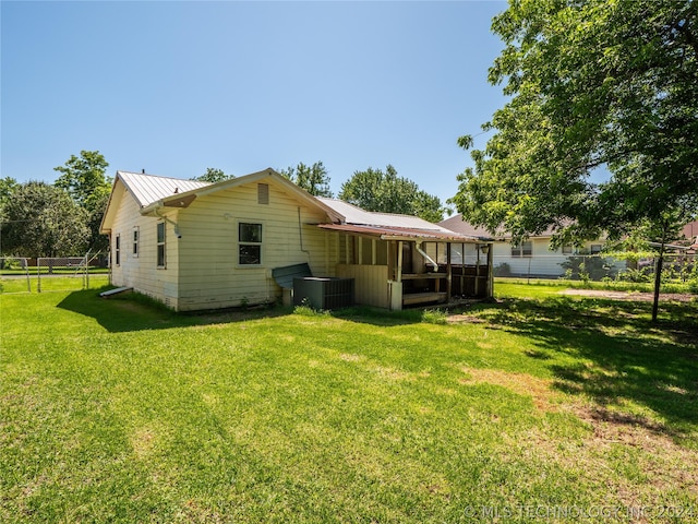 rear view of property with a yard and central AC