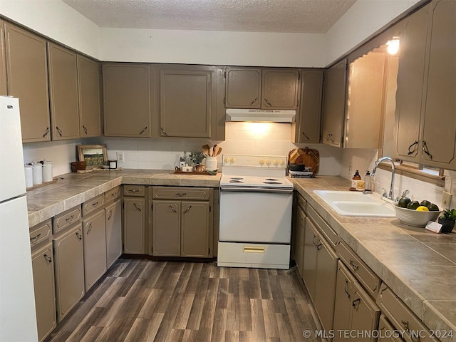 kitchen with a sink, white appliances, dark wood finished floors, a textured ceiling, and under cabinet range hood
