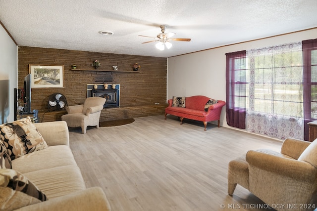 living room featuring a textured ceiling, brick wall, ornamental molding, light hardwood / wood-style flooring, and ceiling fan