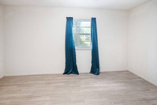 empty room featuring a textured ceiling and light wood-type flooring