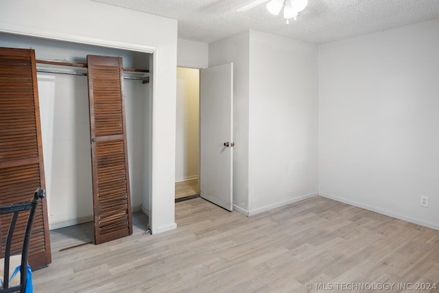 unfurnished bedroom with a textured ceiling, a closet, light wood-type flooring, and ceiling fan