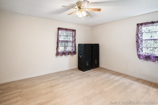 spare room with ceiling fan, a textured ceiling, and light wood-type flooring