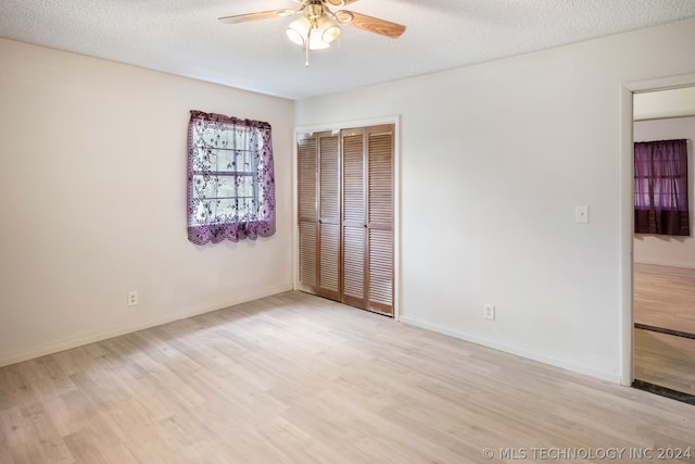 unfurnished bedroom with ceiling fan, a closet, light hardwood / wood-style flooring, and a textured ceiling