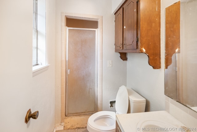 bathroom featuring a shower with shower door, vanity, and toilet