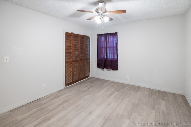 spare room with ceiling fan, light hardwood / wood-style floors, and a textured ceiling