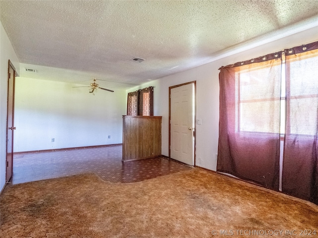 unfurnished room featuring ceiling fan, carpet, and a textured ceiling