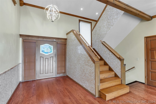 entryway with a chandelier, hardwood / wood-style floors, beamed ceiling, and crown molding