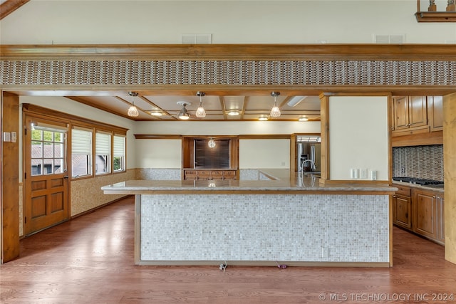 kitchen featuring a center island with sink, decorative light fixtures, wood-type flooring, and appliances with stainless steel finishes