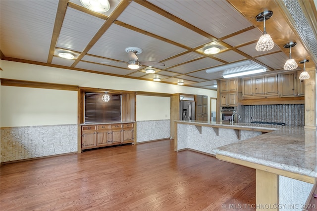 kitchen with hardwood / wood-style flooring, decorative light fixtures, stainless steel appliances, and a breakfast bar area