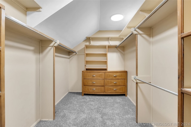 walk in closet with light colored carpet and lofted ceiling