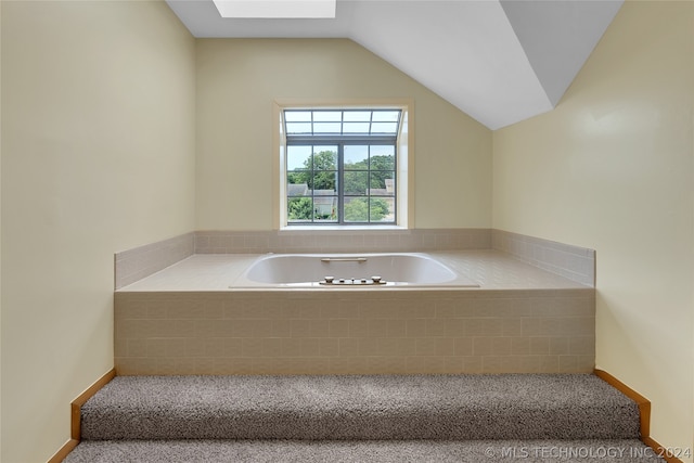 bathroom featuring lofted ceiling and tiled tub