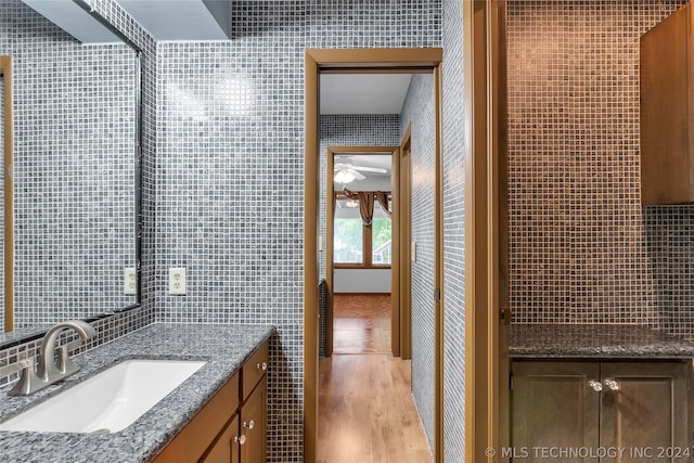 bathroom with decorative backsplash, wood-type flooring, vanity, and tile walls