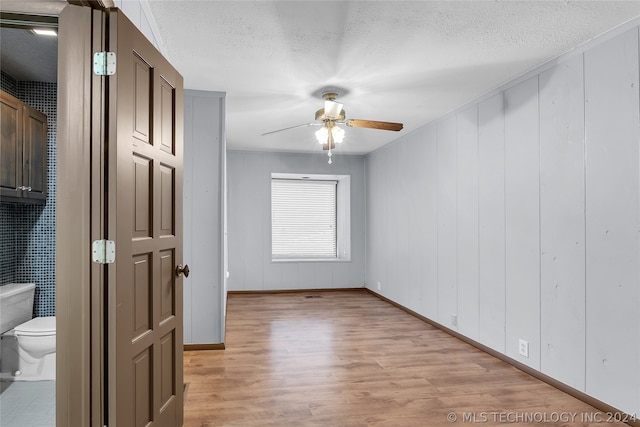 empty room featuring ceiling fan, a textured ceiling, and light hardwood / wood-style flooring