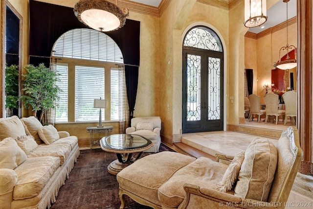 entryway featuring wood-type flooring, crown molding, a towering ceiling, and french doors