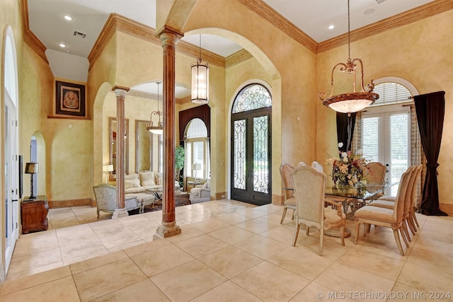 tiled entrance foyer with decorative columns, ornamental molding, a towering ceiling, and french doors