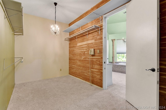 spacious closet with light carpet and an inviting chandelier