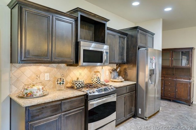 kitchen with decorative backsplash, dark brown cabinets, light stone countertops, and appliances with stainless steel finishes