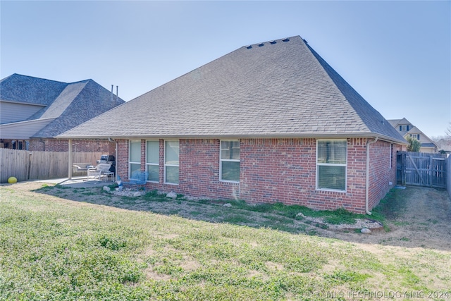 back of house with a patio and a lawn