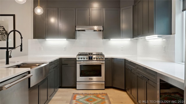 kitchen featuring appliances with stainless steel finishes, tasteful backsplash, sink, light hardwood / wood-style flooring, and hanging light fixtures