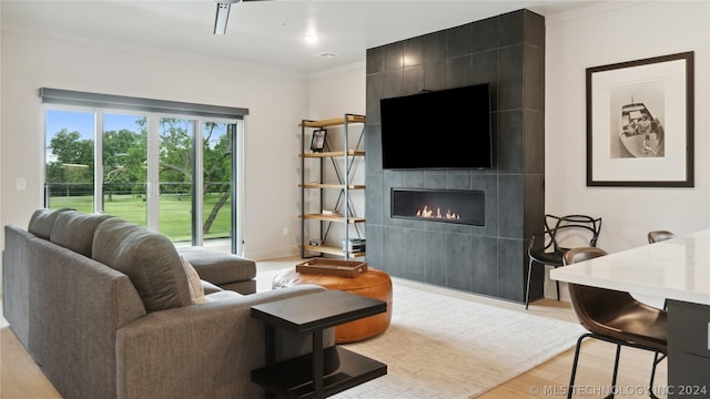 living room featuring a tile fireplace, light wood-type flooring, and crown molding