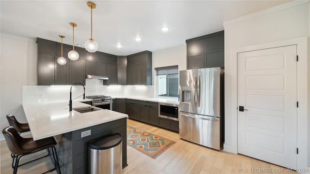 kitchen with pendant lighting, a breakfast bar, light hardwood / wood-style flooring, kitchen peninsula, and stainless steel appliances