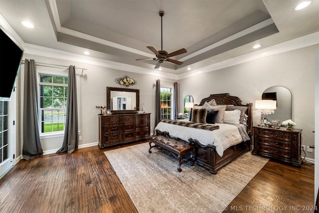 bedroom featuring crown molding, dark hardwood / wood-style floors, a tray ceiling, and ceiling fan