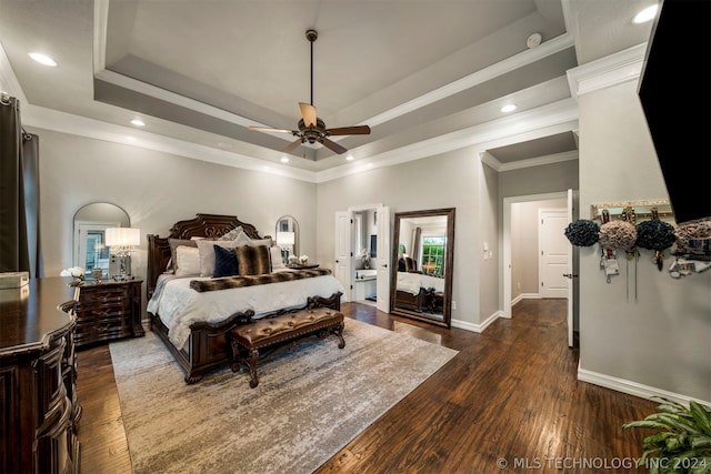 bedroom with ornamental molding, ceiling fan, a raised ceiling, ensuite bathroom, and dark hardwood / wood-style flooring