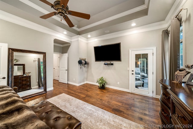 living room with dark hardwood / wood-style floors, a tray ceiling, a healthy amount of sunlight, ornamental molding, and ceiling fan