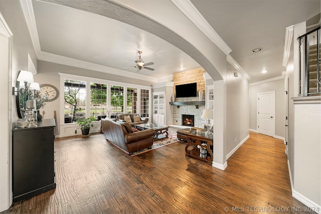 living room featuring ceiling fan, crown molding, wood-type flooring, and a fireplace