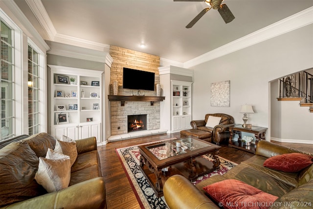 living room with a fireplace, dark hardwood / wood-style floors, crown molding, built in shelves, and ceiling fan