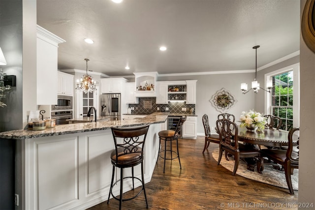 kitchen featuring dark wood-type flooring, appliances with stainless steel finishes, kitchen peninsula, and white cabinets