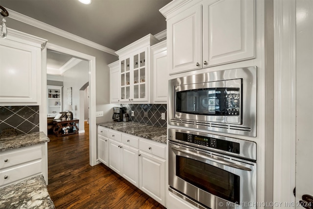 kitchen with white cabinets, stainless steel appliances, backsplash, and dark hardwood / wood-style floors