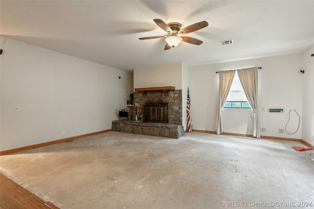 unfurnished living room featuring a stone fireplace, ceiling fan, and concrete flooring