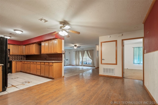 kitchen with ceiling fan, light hardwood / wood-style floors, a textured ceiling, and tasteful backsplash