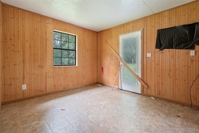 tiled spare room featuring wooden walls