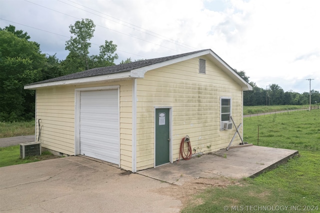 garage featuring a lawn and central AC unit