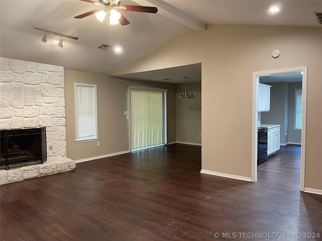 unfurnished living room featuring track lighting, lofted ceiling with beams, ceiling fan with notable chandelier, a fireplace, and dark hardwood / wood-style flooring