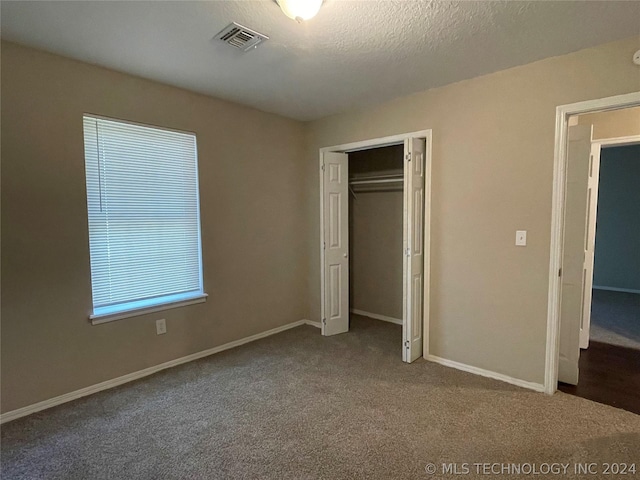 unfurnished bedroom with a closet, carpet floors, and a textured ceiling