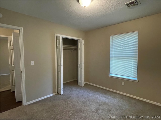 unfurnished bedroom with a closet, carpet, and a textured ceiling